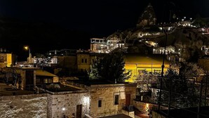 Une vue nocturne d’une ville historique, avec ses bâtiments en pierre et un imposant édifice perché sur une colline.