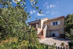 A two-story house with a stone facade, a tiled roof, and a front garden with olive trees. - Colourful Seaview Apartment (Kostrena)