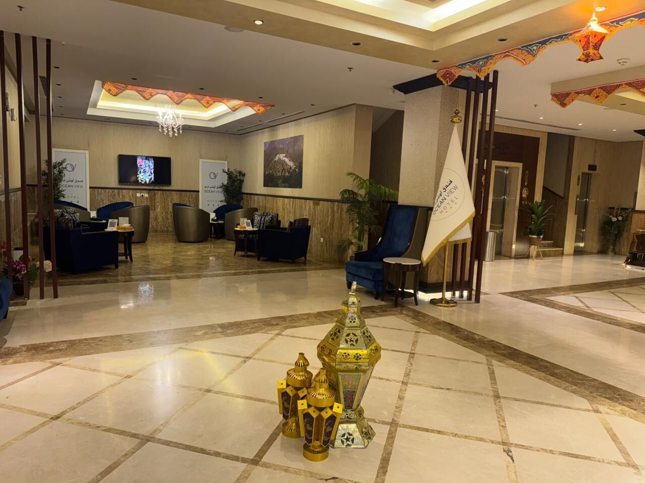 Eine Hotelhalle mit Empfangstresen, Sitzgelegenheiten und einer dekorativen goldenen Struktur.