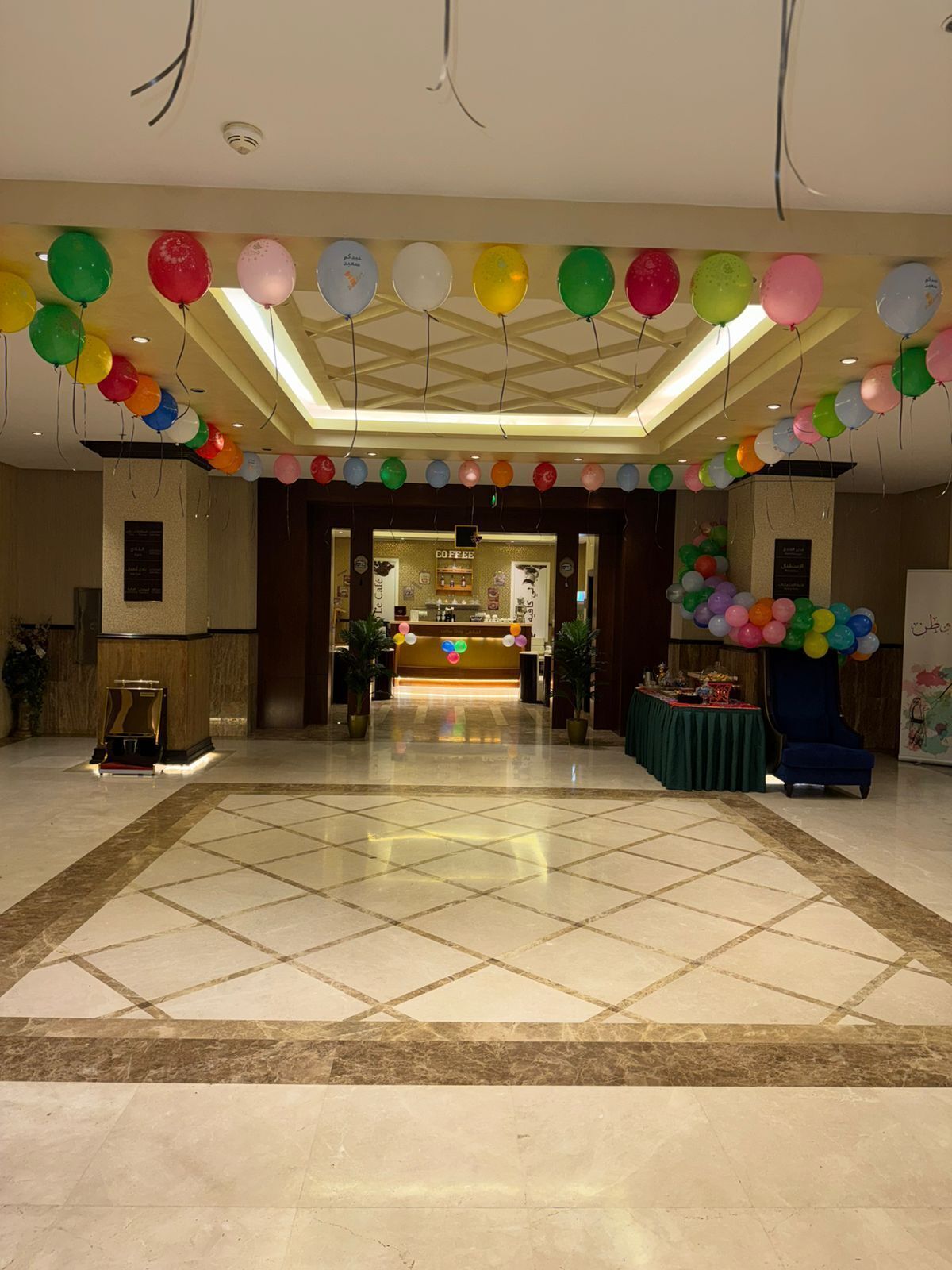 A hotel lobby with a reception desk, a coffee bar, and a tiled floor.