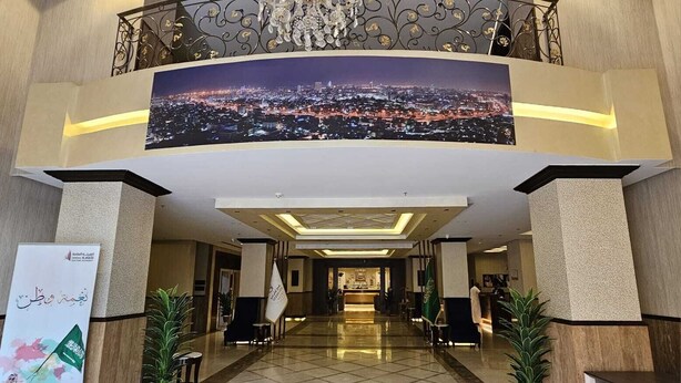 A hotel lobby with a cityscape view, a chandelier, and a reception desk. - Ocean View Al Zahra (Jeddah)