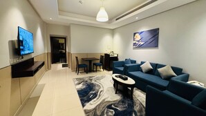 A modern living room with a flat-screen TV, a sofa set, a coffee table, and a dining area with chairs and a table. - Ocean View Al Zahra (Jeddah)