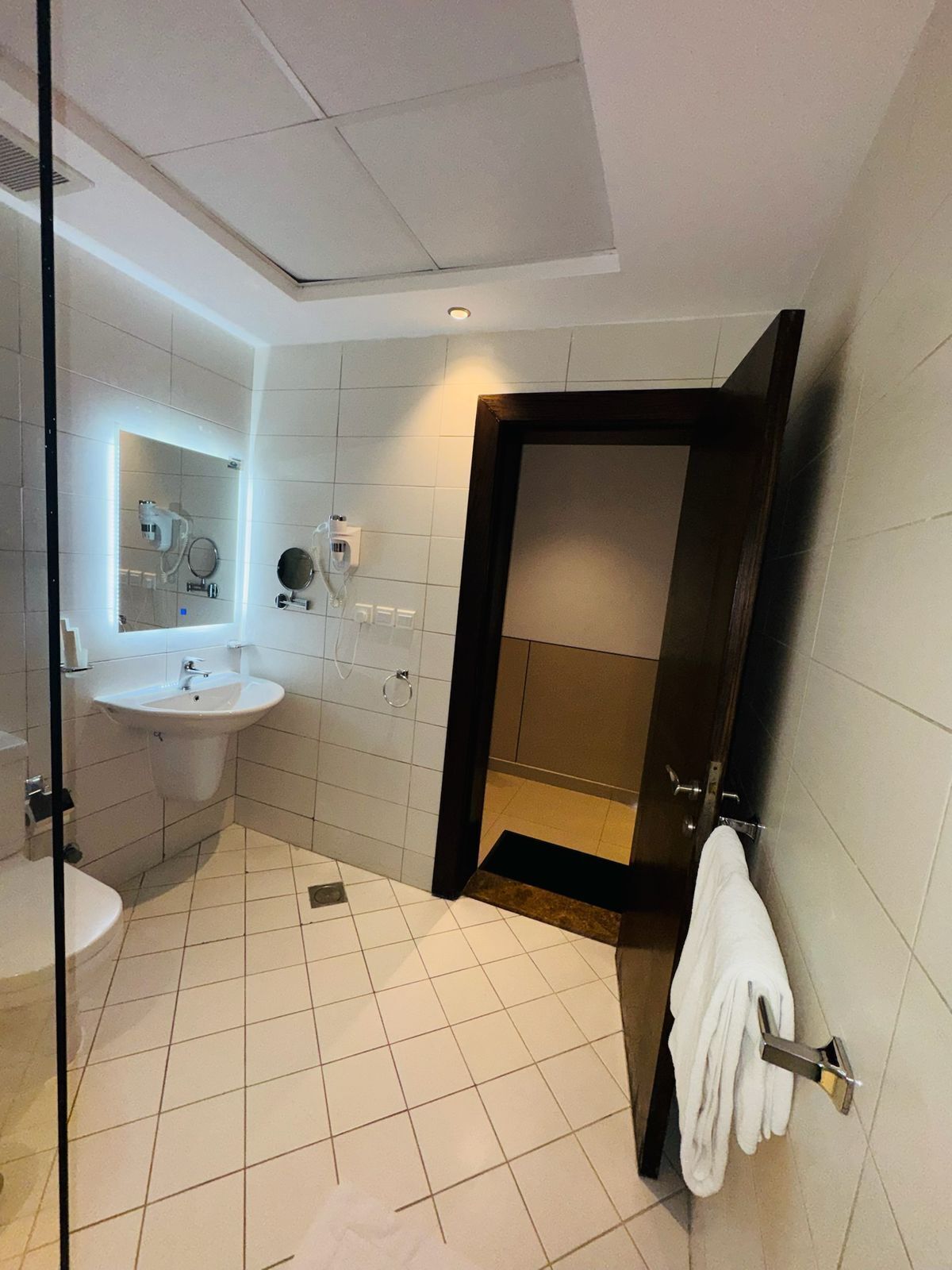 A modern bathroom with a glass shower enclosure, a sink, and a towel rack.