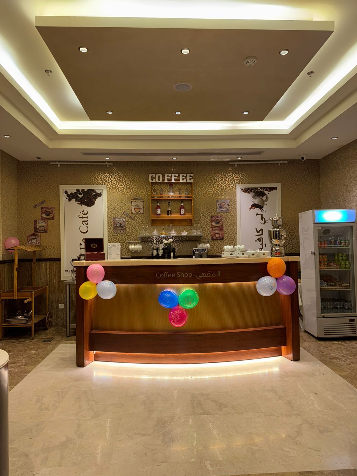 A coffee shop counter with a sign reading 'Coffee Shop' and a decorative wall with various coffee-related items.