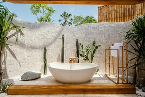 Relax in a serene outdoor space with a bathtub and lush greenery.