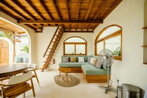 Relax in this inviting space with a plush sofa, wooden table, and arched windows.