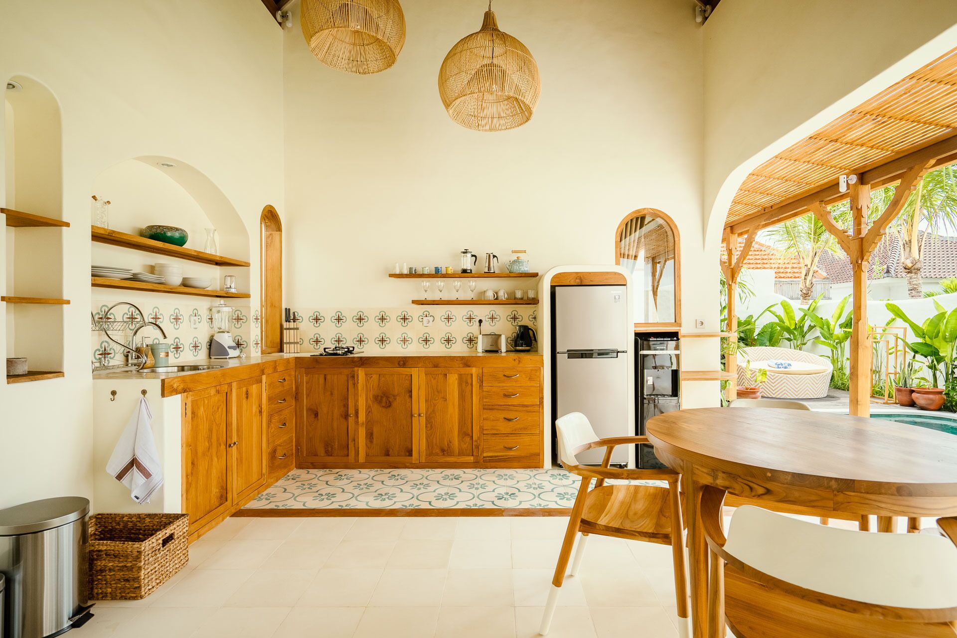 A kitchen with wooden cabinets, a built-in refrigerator, and a dining area with a round table and chairs.