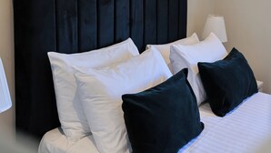 A neatly made bed with white and dark pillows, a black headboard, and a white bedside lamp. - The White City Apartment (Oban)