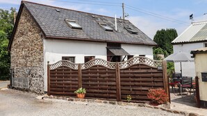 Ein zweigeschossiges Haus mit Naturstein-Fassade, einem geneigten Dach und einem Holzzaun mit Gitterverzierungen.