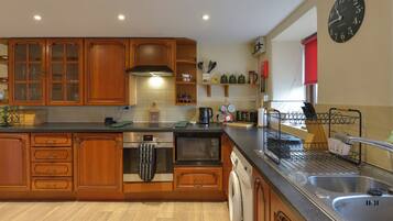 A kitchen with wooden cabinets, a built-in oven, a washing machine, and a sink.