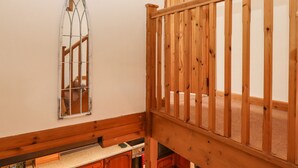 Eine Holztreppe mit Handlauf, einer Holzbrüstung und einem farbigen Glasfenster.