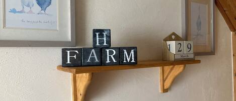 Una estantería de madera con bloques que deletrean "HARM" y un bloque con forma de casa de madera con la fecha "1 29 de marzo".