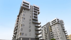 Een meerlaags woongebouw met balkons, een zichtbaar ‘1C’ bord en een heldere lucht.