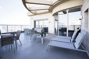 Eine moderne Terrasse im Freien mit Essbereich, Lounge-Stühlen und einer Glasreling.