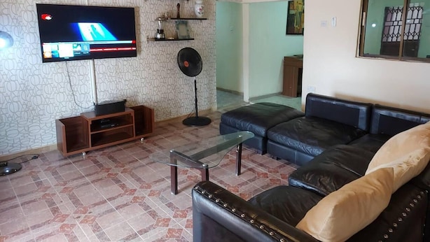 Ein Wohnzimmer mit Fernseher, Ledersofa und Ventilator.