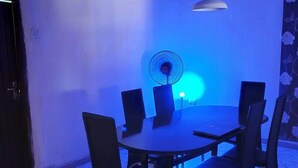 Ein Essbereich mit einem runden Tisch, schwarzen Stühlen, einem Ventilator und einer Pendelleuchte.