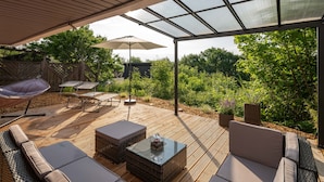 An outdoor patio with a pergola, cushioned seating, and a table. - RhönKristall modern terrace house with a far-reaching view (Bischofsheim in der Rhön)