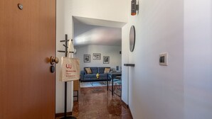 A hallway with a wooden door, a bag hanging on a rack, a sofa, and a table with chairs. - Le terrazze nel cuore della Kalsa by Wonderful Italy (Palermo)