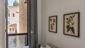 A hotel room with a balcony, a bed, a nightstand, and two framed botanical prints on the wall. - Casa Brunaccini con Terrazza by Wonderful Italy (Palermo)