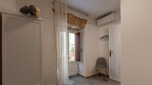 Un corridoio con una porta bianca, una sedia grigia e una finestra che si affaccia all'esterno.