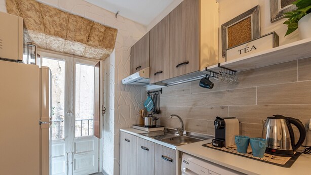 Una cucina moderna con lavatrice integrata, una macchina per il caffè e una dispensa per il tè.