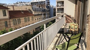 Ein Balkon mit Tisch und Stühlen, der Blick auf eine Skyline mit verschiedenen Gebäuden freigibt.