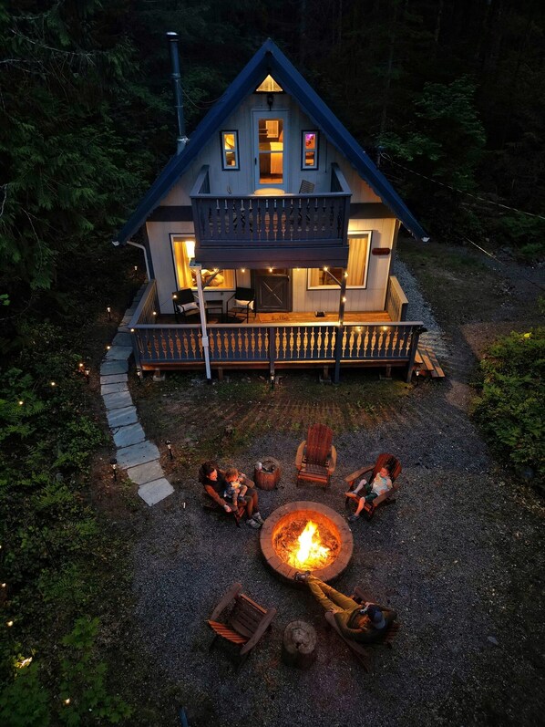 Een knus huisje met balkon, vuurkorf en buitenmeubilair.