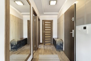 A hallway with wooden flooring, benches, and a mirrored wall.