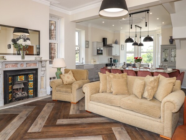 A spacious living room with a fireplace, a dining area, and a kitchen.
