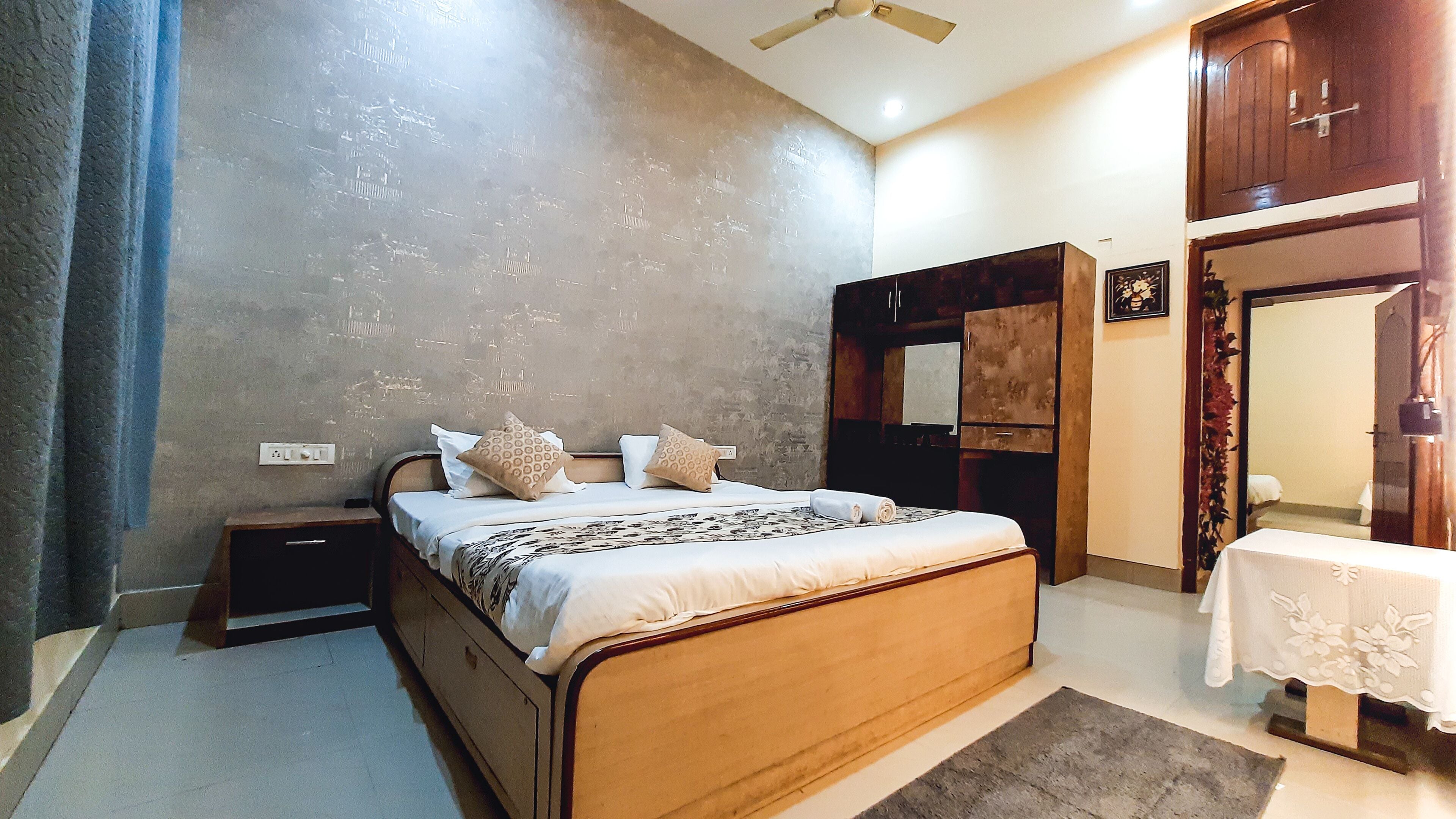 Un dormitorio con cama, mesitas de noche, armario, espejo y una mesa con mantel.