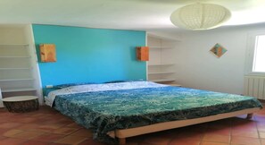 Een slaapkamer met een bed, een houten hoofdeinde, een blauwe wand, een raam en een plafondlamp.