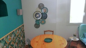 En matplats med ett runt träbord, två stolar och en väggdekoration bestående av ett arrangemang av dekorativa tallrikar.