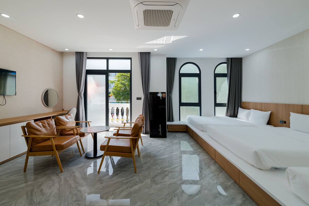 A hotel room with a bed, a seating area with chairs, a TV, and a large window.