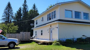 A two-story house with a front porch, a satellite dish, and a wooden fence.