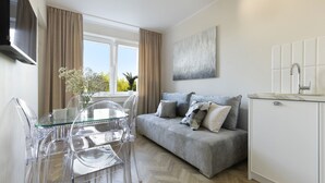 Una sala moderna con un sofá gris, una mesa de comedor de vidrio transparente y sillas.