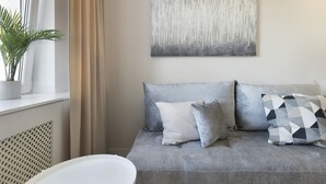 Un salón moderno con un sofá gris, un cojín de estampado geométrico y un cuadro abstracto minimalista en la pared.
