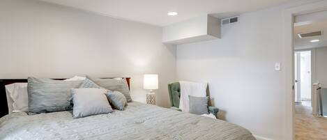 A bedroom with a large bed, a bedside table with a lamp, and a chair.