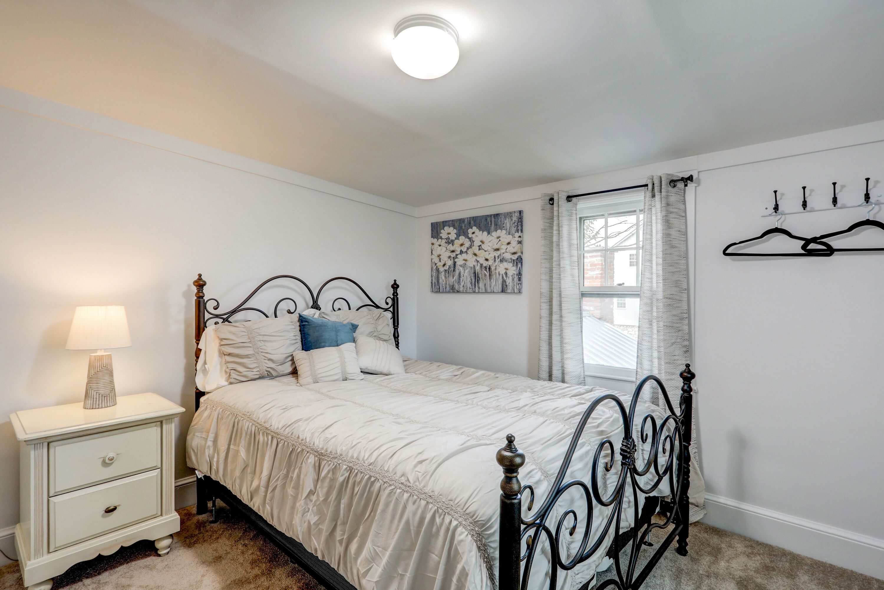 A bedroom with a bed, nightstand, lamp, and a window with curtains.