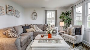 A living room with a sectional sofa, a coffee table with a vase, and a clock on the wall.