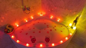 A bathtub with rose petals and candles, a fruit basket, and a bottle of wine. - Cordial Cappadocia Hotel (Ürgüp)