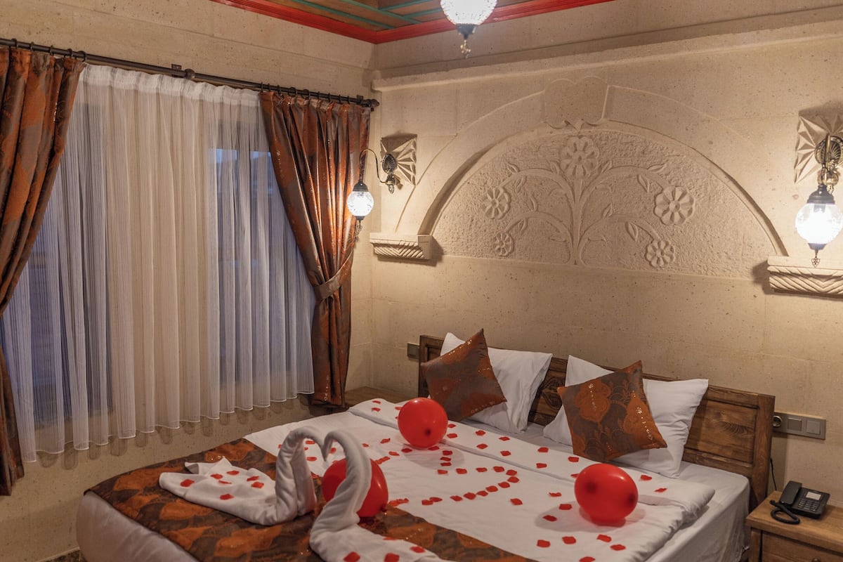 A bedroom with a wooden bed, a decorative headboard, a bedside table, and a patterned rug.