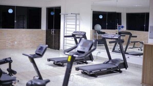 Un gimnasio con cintas de correr, bicicletas estáticas y una máquina de remo.