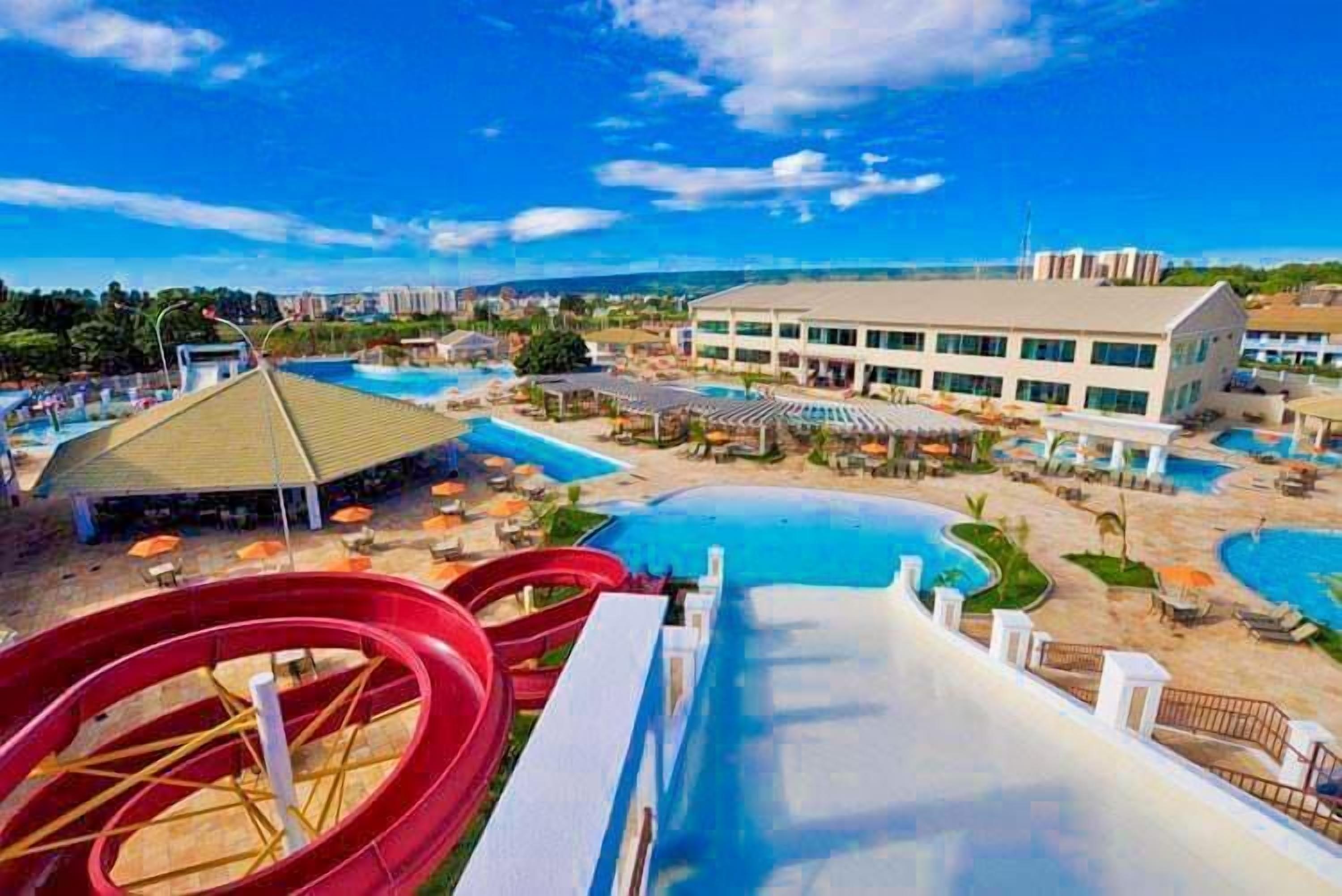 Un resort con varias piscinas, un tobogán acuático y un edificio grande con techo plano.