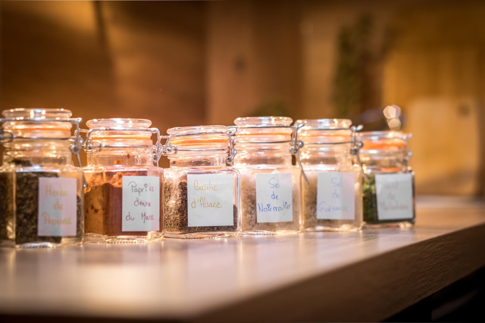 A row of glass jars with labels on a wooden surface.