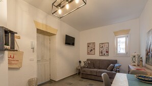 Ein Wohnzimmer mit einer Couch, einem Fernseher und einem Esstisch.