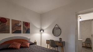 Ein Schlafzimmer mit Bett, Schreibtisch, Stuhl und einem Kunstwerk an der Wand.