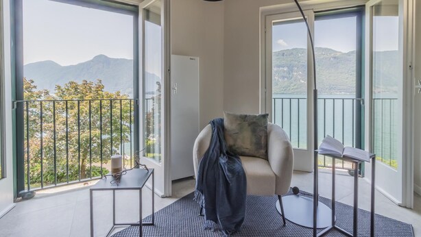 A modern room with a large window, a round table, a chair, and a floor lamp.
