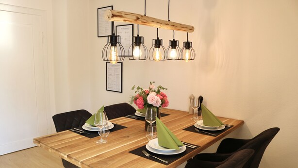A dining table set with plates, glasses, and a vase of flowers. - Modern vacation apartment in the Allgäu (Erkheim)