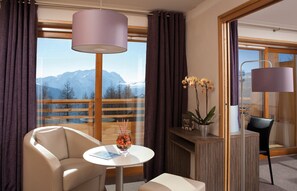 A modern room with a view of mountains, a sofa, a small table with a glass, and a vase of flowers. - Lagrange Vacances L'Alpenrose (Huez)