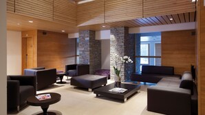 A modern lobby with a stone accent wall, leather seating, and a wooden ceiling. - Lagrange Vacances L'Alpenrose (Huez)